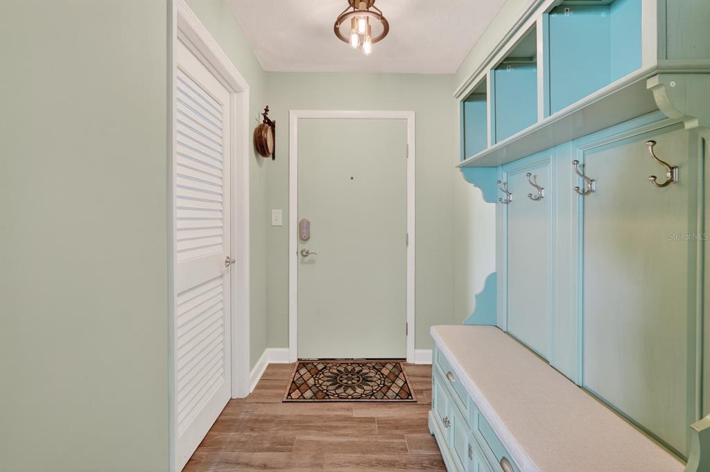 An entryway features light green walls, a built-in bench with storage, and wood-look flooring — 2860 OCEAN SHORE BOULEVARD UNIT 2060, ORMOND BEACH, FL