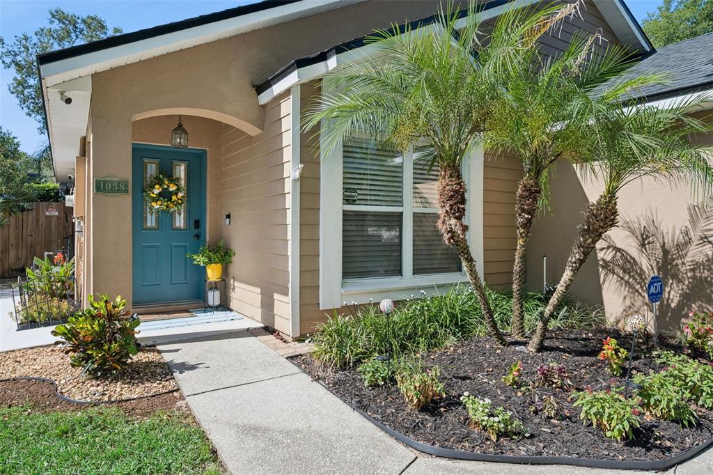 The exterior of a house features a blue front door, a palm tree, and landscaping — 1038 ROYAL OAKS DRIVE, APOPKA, FL