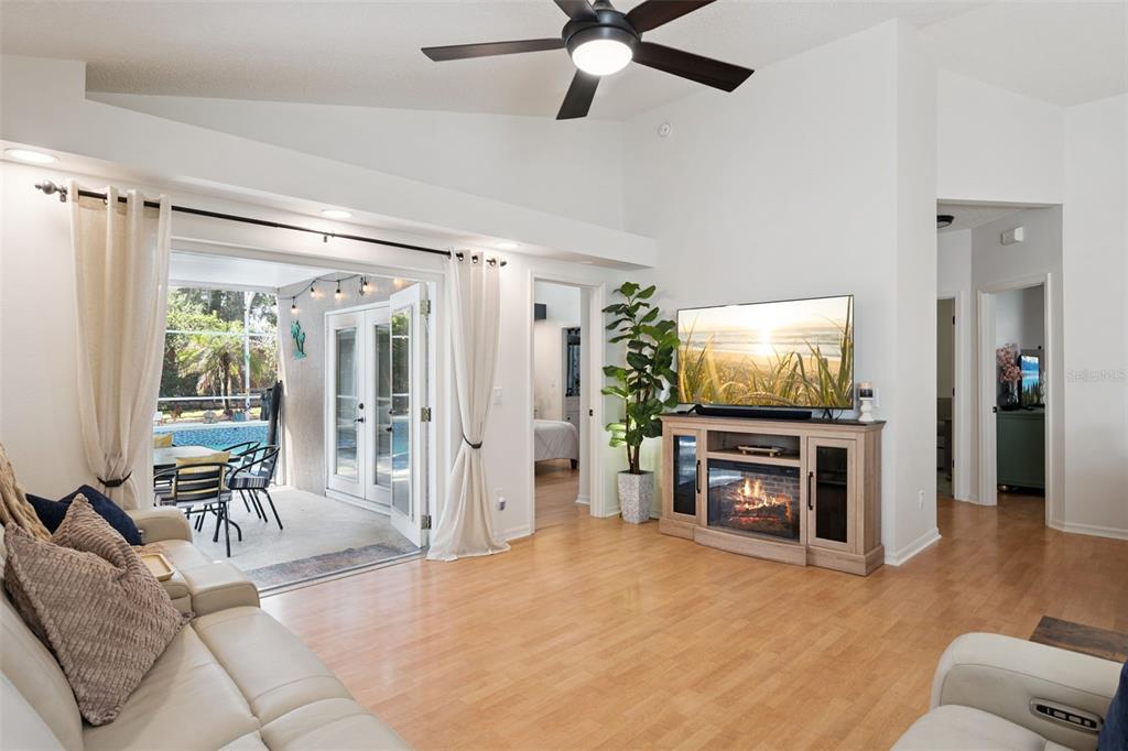 A living room features light wood flooring, a fireplace console, and sliding doors to a patio — 1038 ROYAL OAKS DRIVE, APOPKA, FL