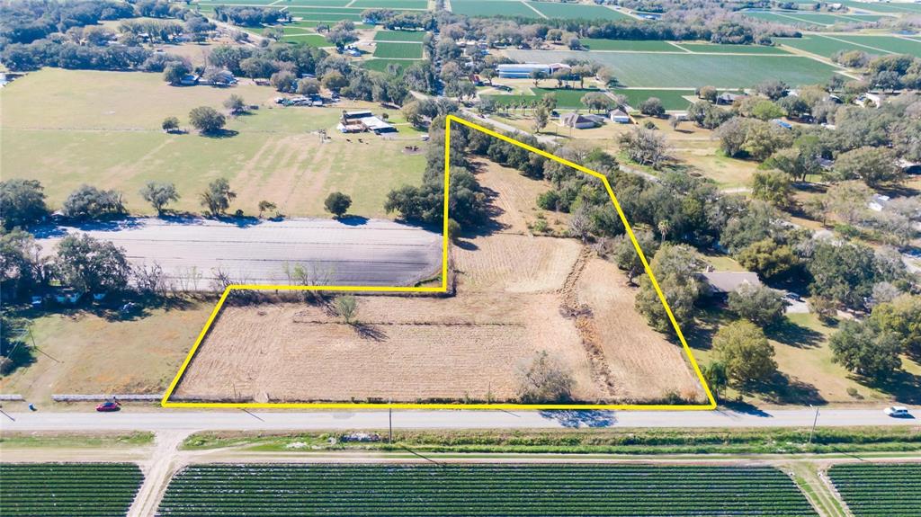 An aerial view shows a vacant, L-shaped plot of land outlined in yellow near a road — S. FORBES ROAD, DOVER, FL