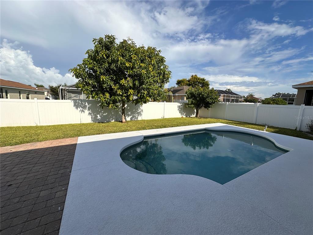 A backyard features a swimming pool, a white vinyl fence, and two large trees — 5010 44TH STREET W, BRADENTON, FL