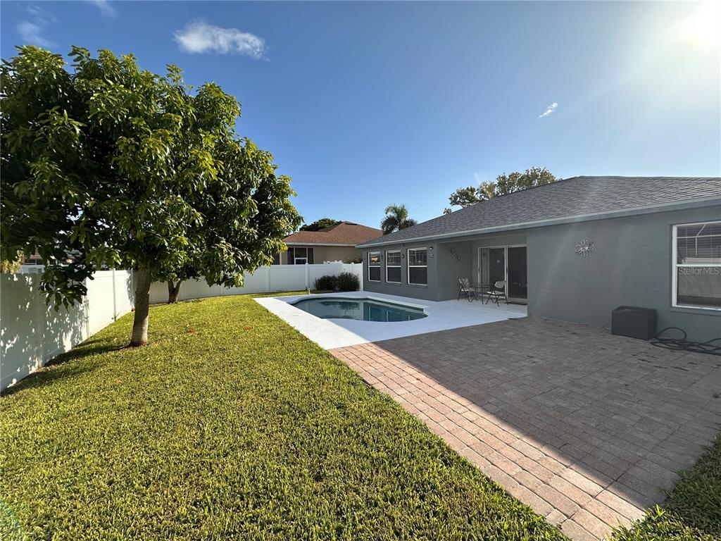 A backyard features a swimming pool, a brick patio, and a large tree on the lawn — 5010 44TH STREET W, BRADENTON, FL