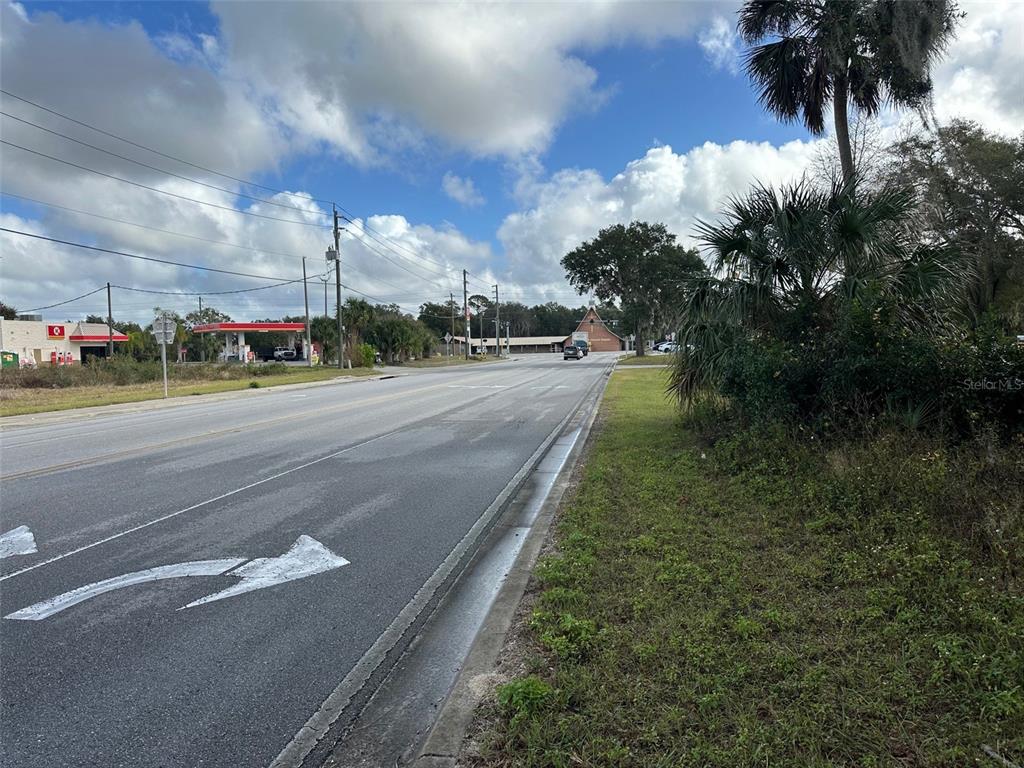 A paved road leads past a gas station toward a building under a cloudy sky — 0 DOYLE ROAD, OSTEEN, FL