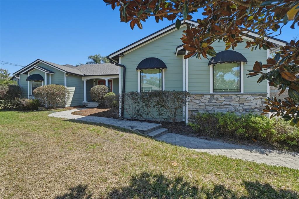 A light green house with stone accents and a stone walkway under a clear sky — 834 MILLSHORE DRIVE, CHULUOTA, FL
