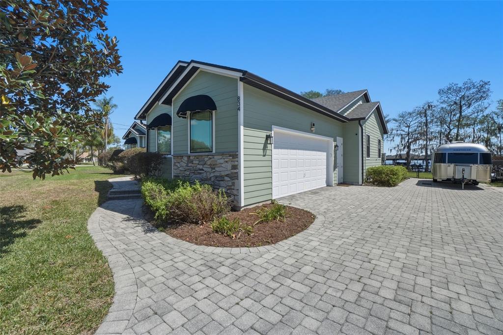 A light green house with a stone facade, white garage door, and paved driveway — 834 MILLSHORE DRIVE, CHULUOTA, FL