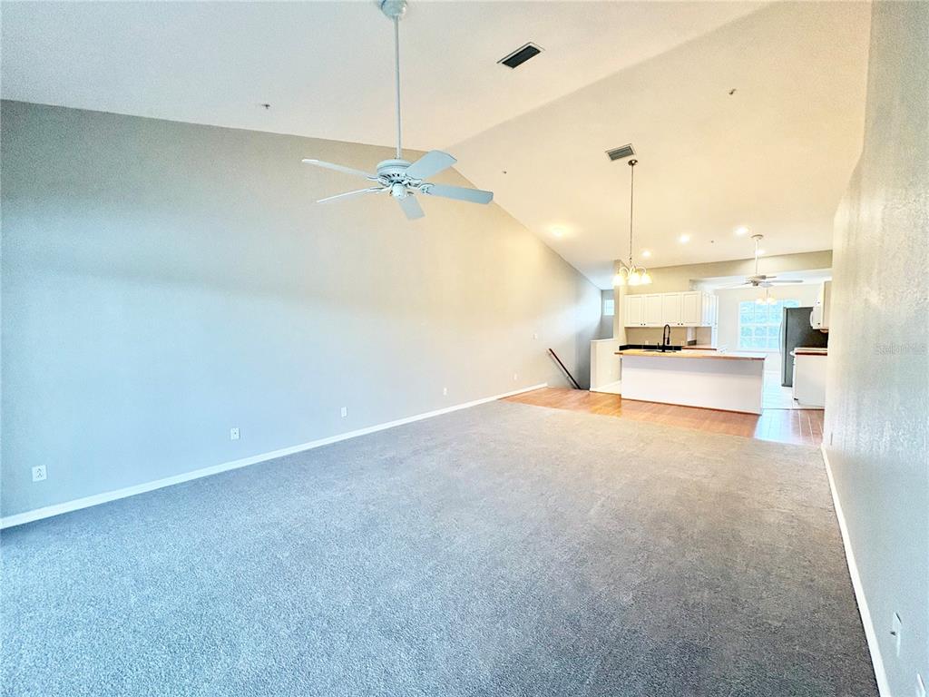 A living room with beige carpet, a vaulted ceiling, a chandelier, and sliding glass doors — 6554 FAIRWAY GARDENS DRIVE UNIT 6554, BRADENTON, FL