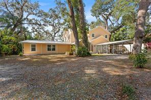 A two-story light-colored house with a gravel driveway and a metal carport — 315 WOOTEN ROAD, LUTZ, FL
