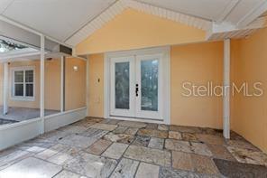 A covered patio features stone flooring and white double doors leading into the home — 315 WOOTEN ROAD, LUTZ, FL