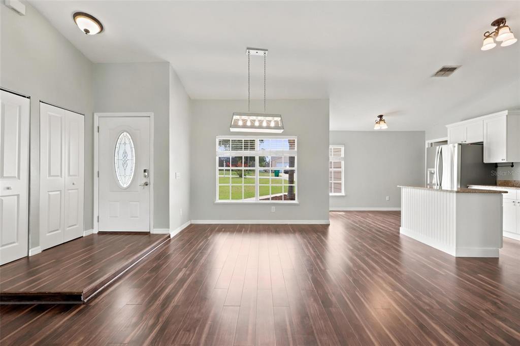 A covered front porch with beige siding, a white front door, and two windows — 2695 KEENE LANE, DELTONA, FL