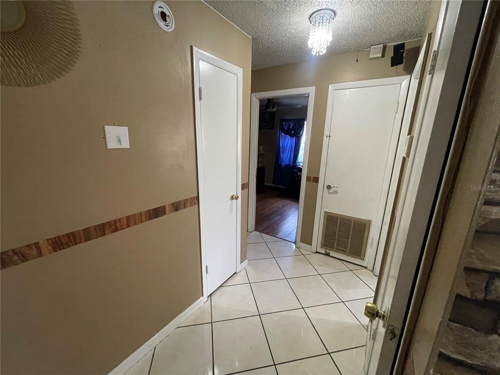 A hallway with tile flooring, beige walls, and three white doors — 126 DAHLIA DRIVE, KISSIMMEE, FL