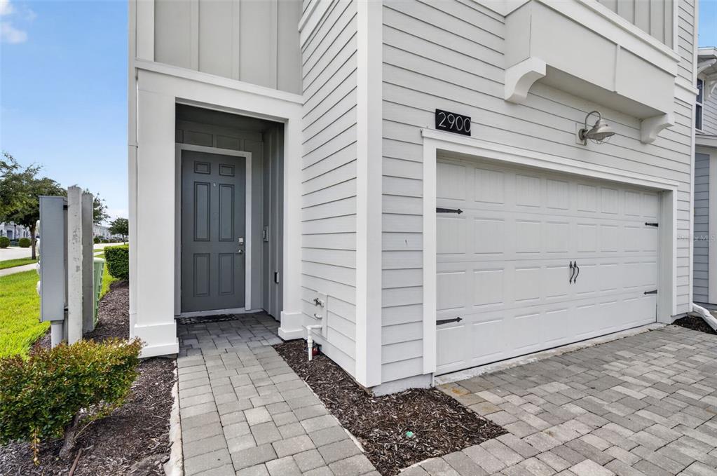A two-story townhouse with light green siding, a two-car garage, and a paver driveway — 2900 TITLE STREET, KISSIMMEE, FL