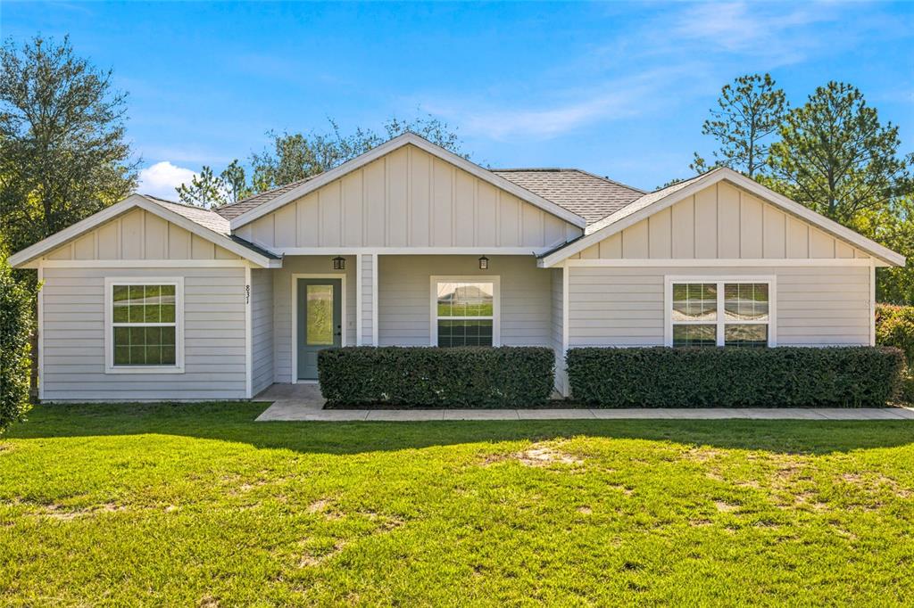 A single-story house with light gray siding, a covered entryway, and a manicured front lawn — 831 NE 150TH AVENUE, WILLISTON, FL