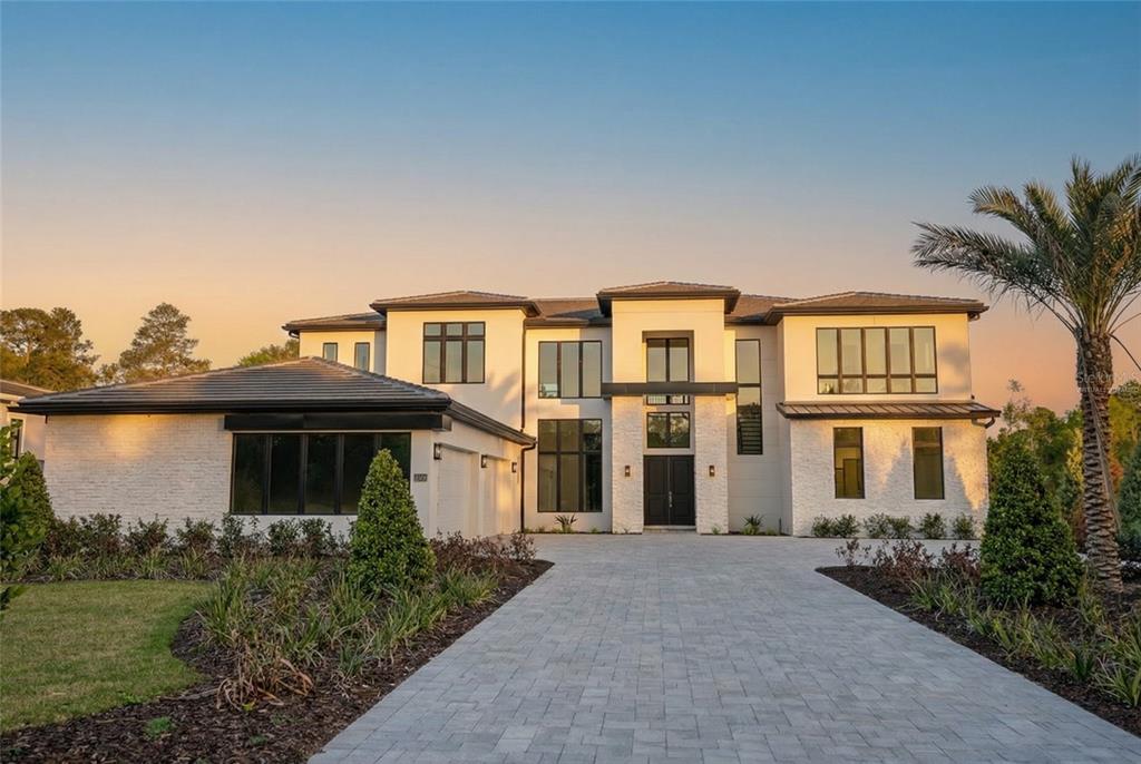 A modern two-story house with white stone siding, a paved driveway, and a palm tree — 16000 PENDIO DRIVE, BELLA COLLINA, FL