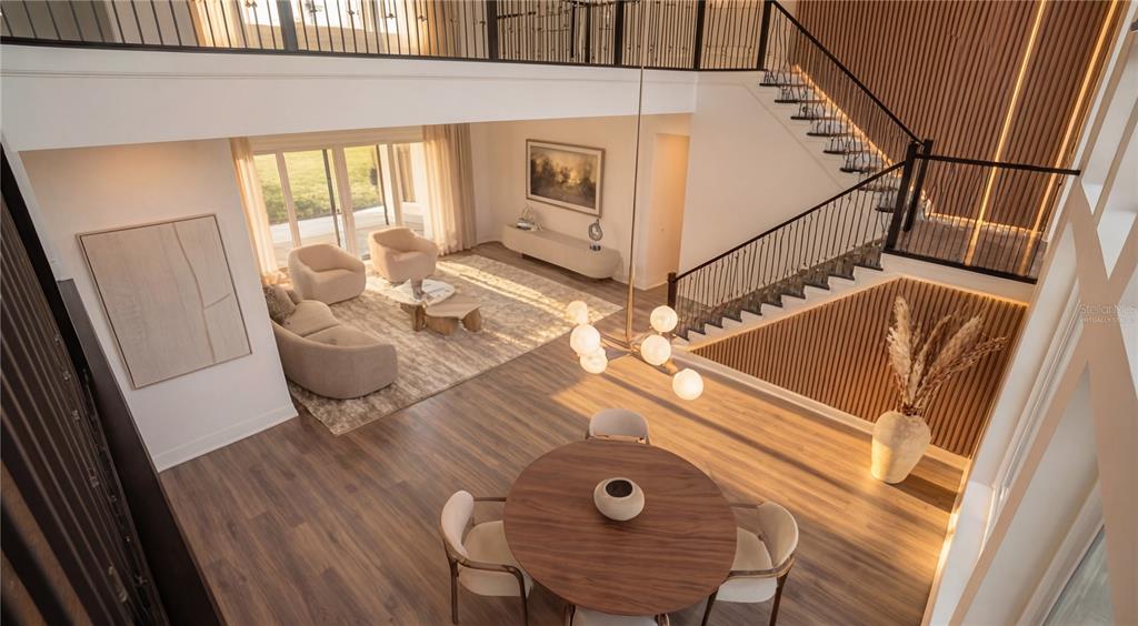 A high-angle view of an open-concept living and dining area with a modern staircase — 16000 PENDIO DRIVE, BELLA COLLINA, FL