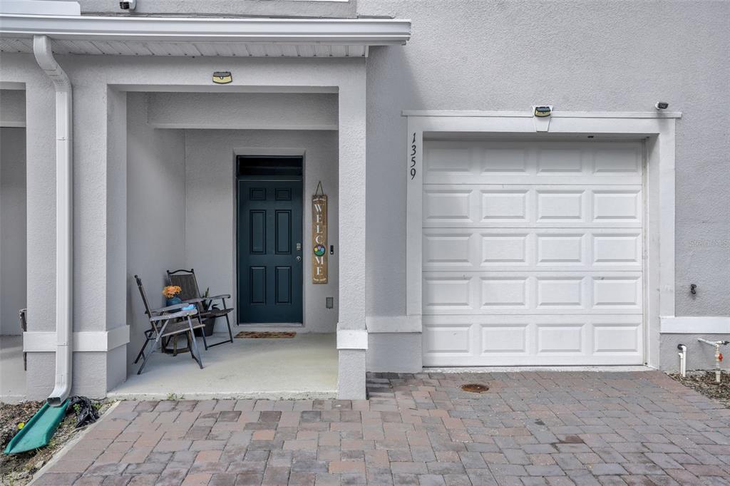 The exterior of a gray townhouse features a covered entryway, a dark door, and a garage — 1359 ISLETA LOOP, KISSIMMEE, FL