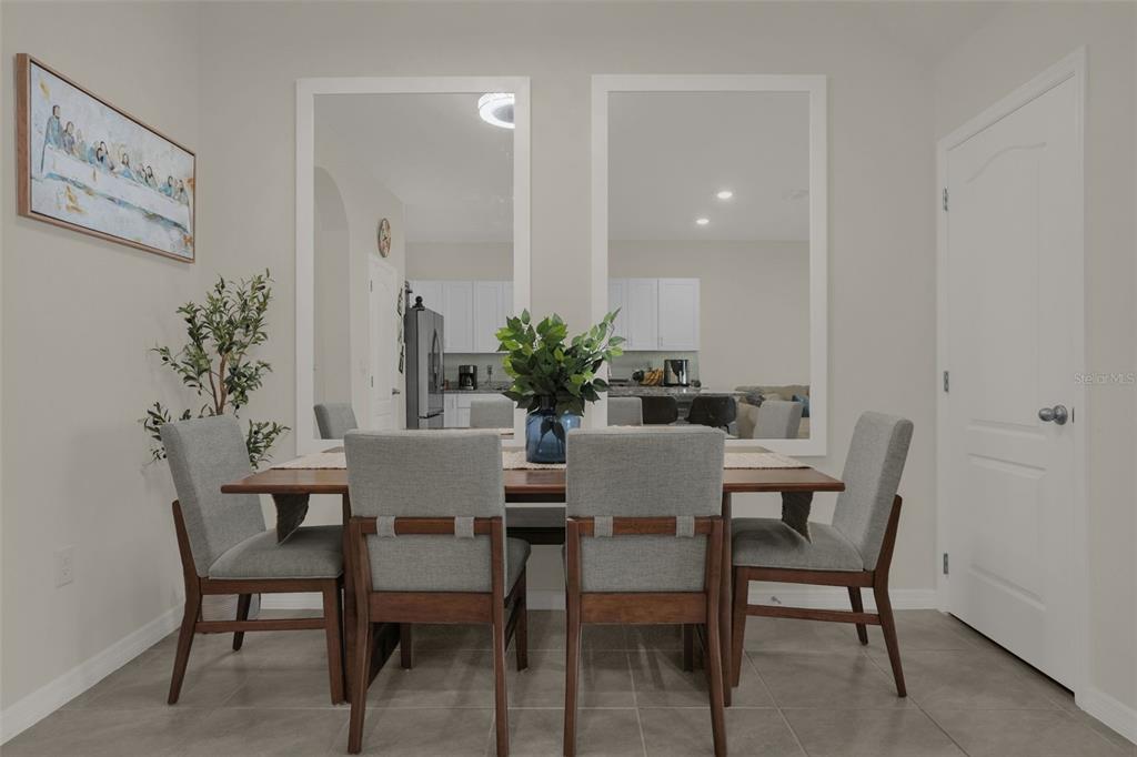 A dining room features a wooden table with four gray chairs and two large mirrors — 1359 ISLETA LOOP, KISSIMMEE, FL