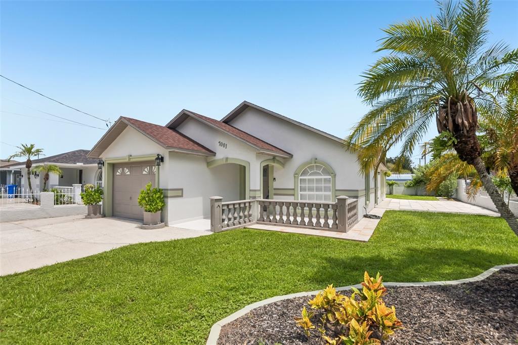 A single-story house with a beige stucco exterior, a garage, and a decorative stone balustrade — 7001 N CLARK AVENUE, TAMPA, FL