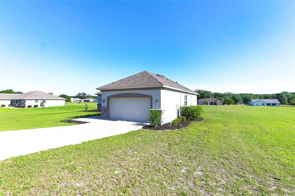 A detached garage with a concrete driveway sits on a large, grassy residential lot — 725 E CHARLESTON COURT, HERNANDO, FL