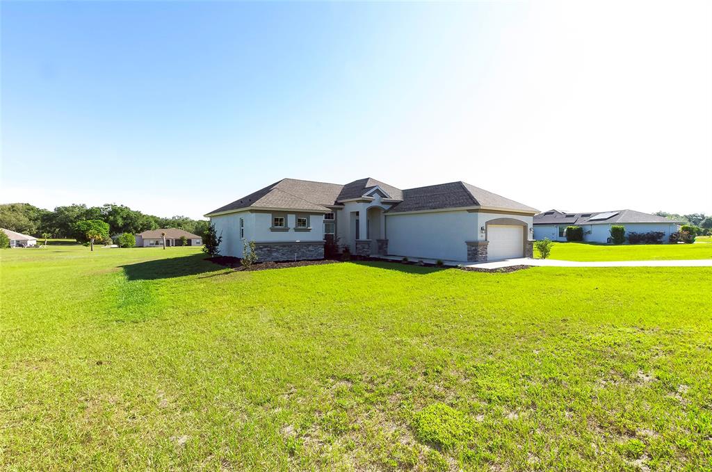 A single-story house with a tan exterior, stone accents, and a two-car garage — 725 E CHARLESTON COURT, HERNANDO, FL