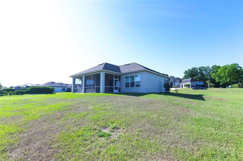 A rear view of a single-story house with a screened-in lanai and a grassy yard — 725 E CHARLESTON COURT, HERNANDO, FL