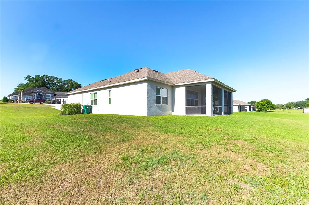 A single-story house with a screened-in lanai sits on a large, grassy lot — 725 E CHARLESTON COURT, HERNANDO, FL