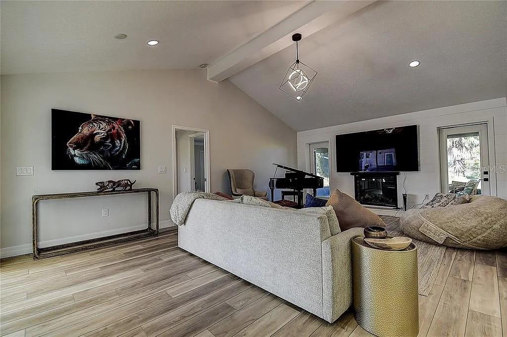 A living room features a vaulted ceiling, light wood flooring, a sofa, and a piano — 4723 THOMAS HOBY PLACE, SARASOTA, FL