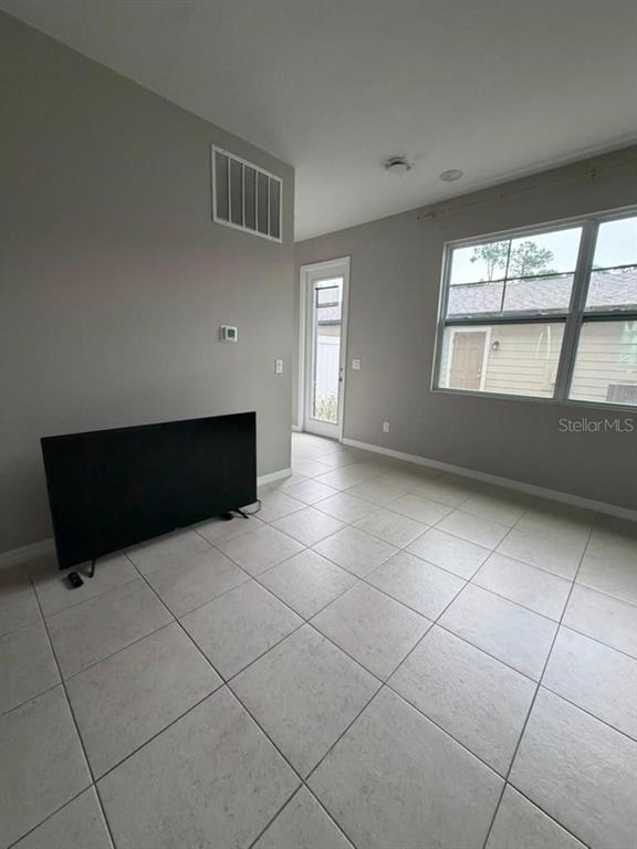 A room with light gray walls, tile flooring, a television, and a glass-paneled door — 11165 LIME FLOWER DRIVE, WINTER GARDEN, FL