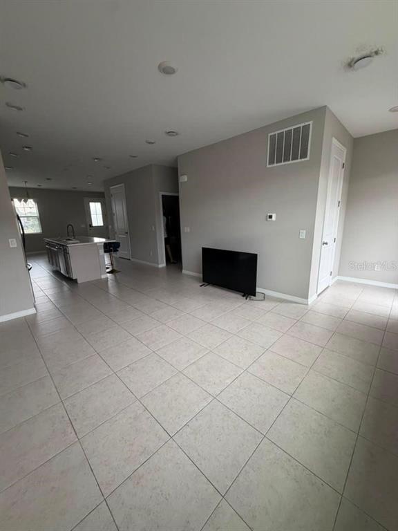 An open-concept living area features light-colored tile flooring, gray walls, and a kitchen island — 11165 LIME FLOWER DRIVE, WINTER GARDEN, FL