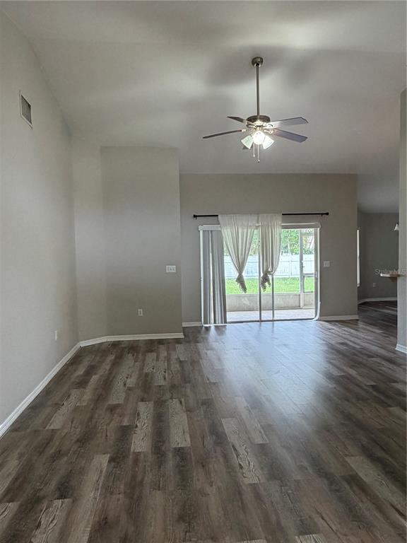 A living room features wood-look flooring, a ceiling fan, a wall-mounted television, and sliding doors — 5619 FISCHER DRIVE, LAKELAND, FL