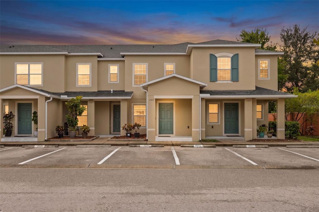 A tan, two-story townhouse complex features multiple entrances and a paved parking lot in front — 2523 SANDY BEACH LANE, CLEARWATER, FL