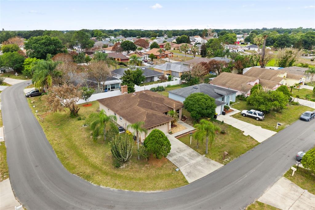 An aerial view shows a suburban neighborhood with single-story homes, driveways, and palm trees — 329 LAKE DAISY LOOP, WINTER HAVEN, FL
