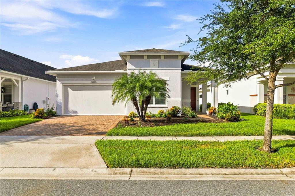 A single-story house with a paved driveway, a two-car garage, and a small palm tree — 5006 E FOUNTAINWOOD DRIVE, ST CLOUD, FL