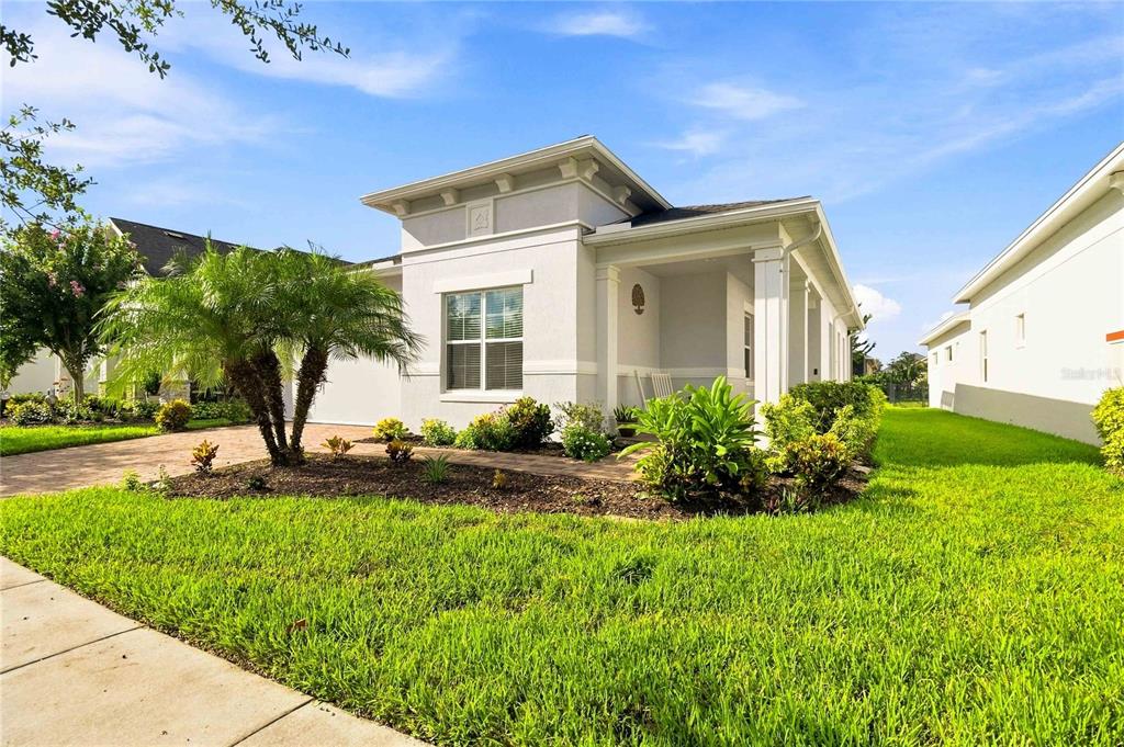 A single-story house with a white stucco exterior, a covered front porch, and landscaped yard — 5006 E FOUNTAINWOOD DRIVE, ST CLOUD, FL