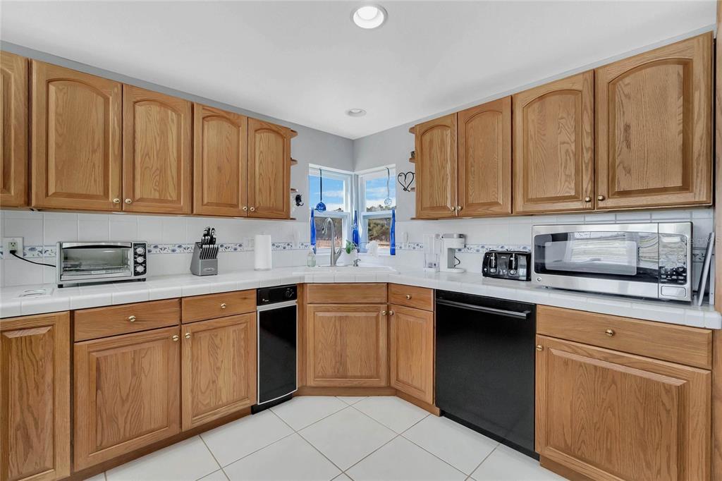 An entryway with white tile floors, a red front door, and an adjacent sunlit seating area — 16131 JOHNS LAKE ROAD, CLERMONT, FL
