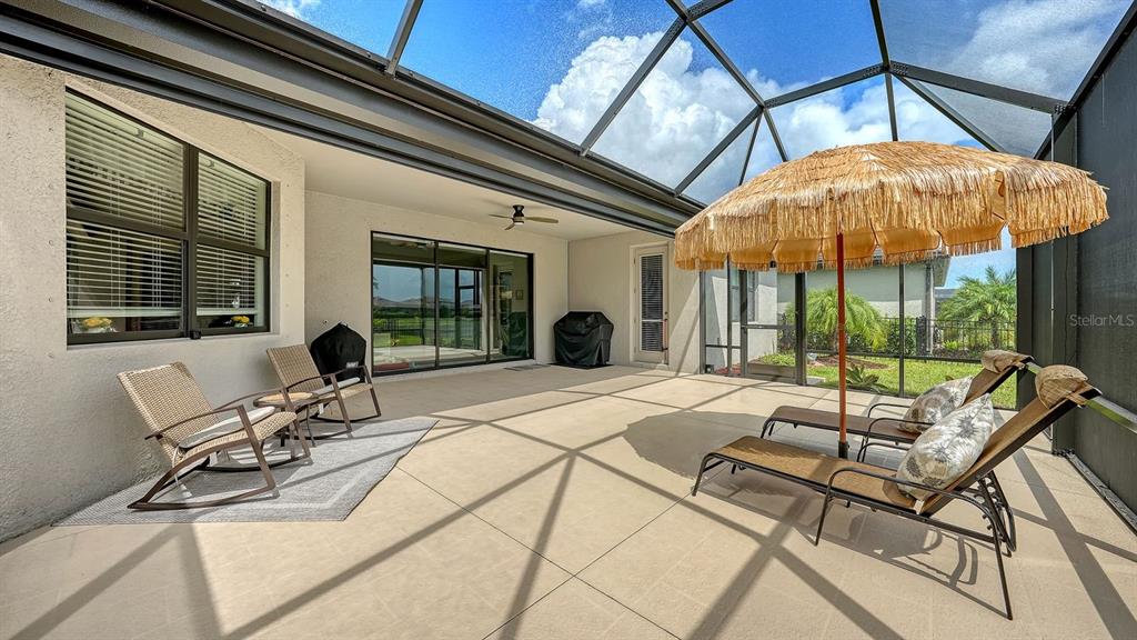 A kitchen features white cabinetry, a large central island with bar seating, and pendant lighting — 4971 OYSTER PEARL STREET, BRADENTON, FL