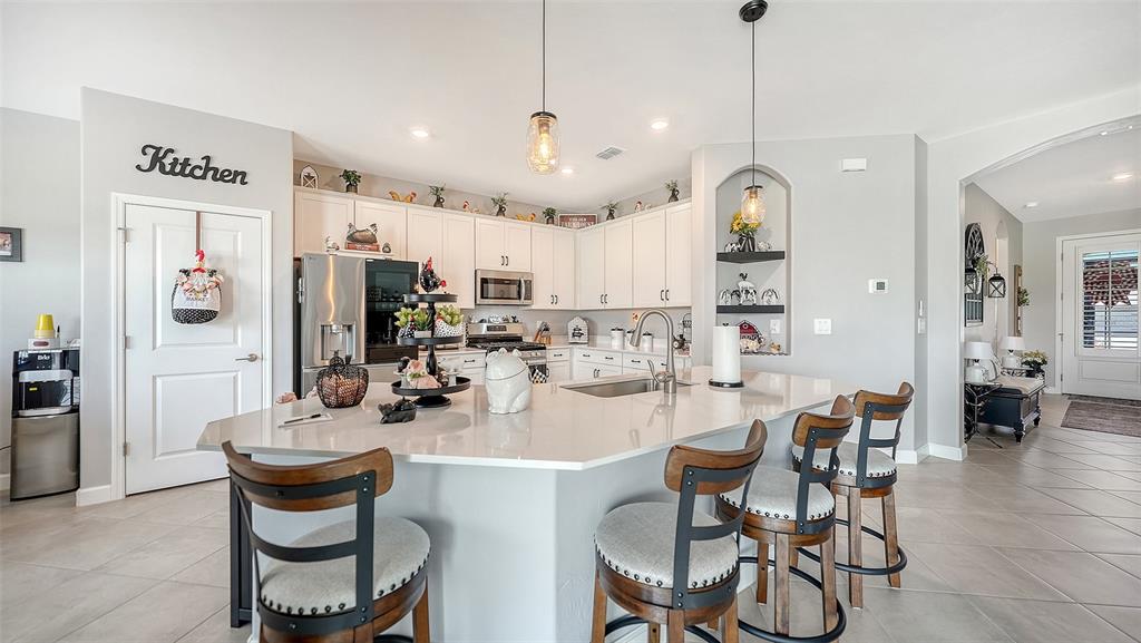 A kitchen features white cabinets, stainless steel appliances, and a dining area with a table — 4971 OYSTER PEARL STREET, BRADENTON, FL