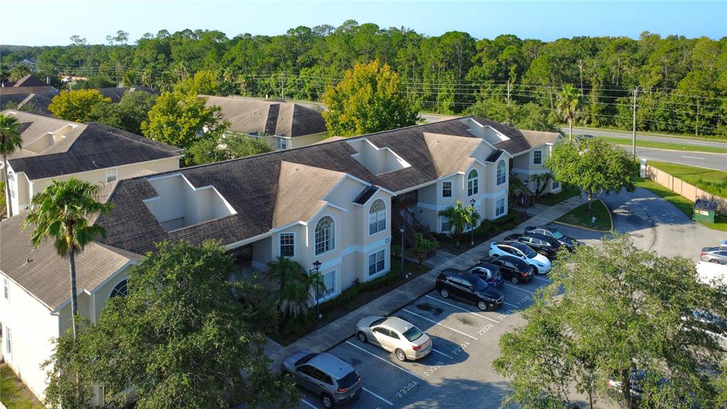 An aerial view shows a multi-story apartment building with a parking lot in front — 2332 PRIME CIRCLE UNIT B, KISSIMMEE, FL