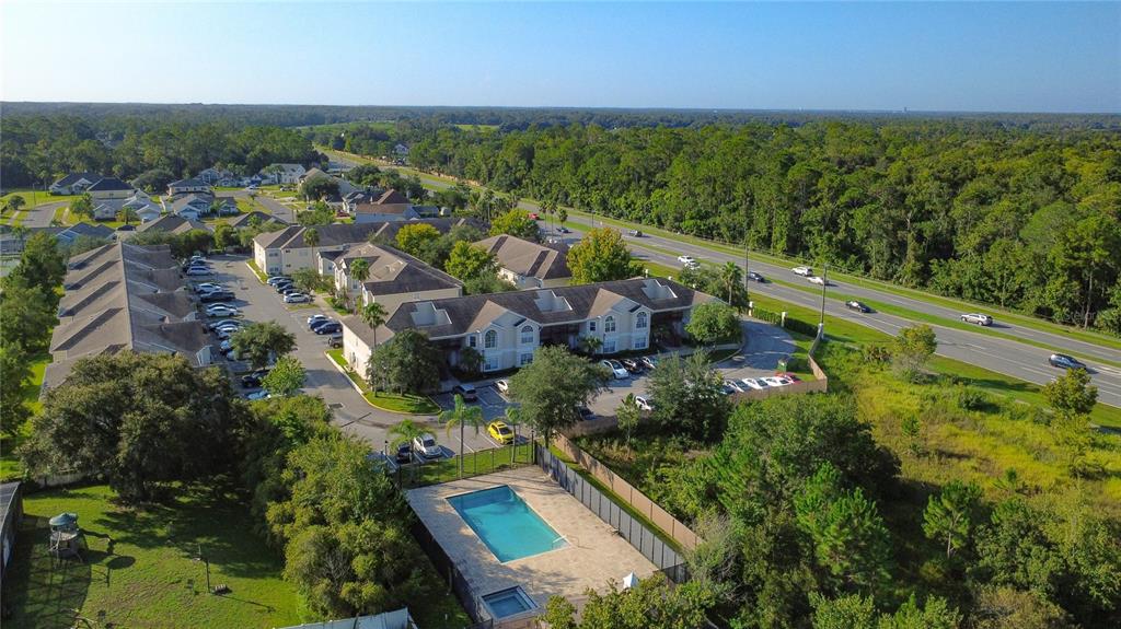 An aerial view shows a multi-unit apartment complex with a swimming pool and parking lot — 2332 PRIME CIRCLE UNIT B, KISSIMMEE, FL