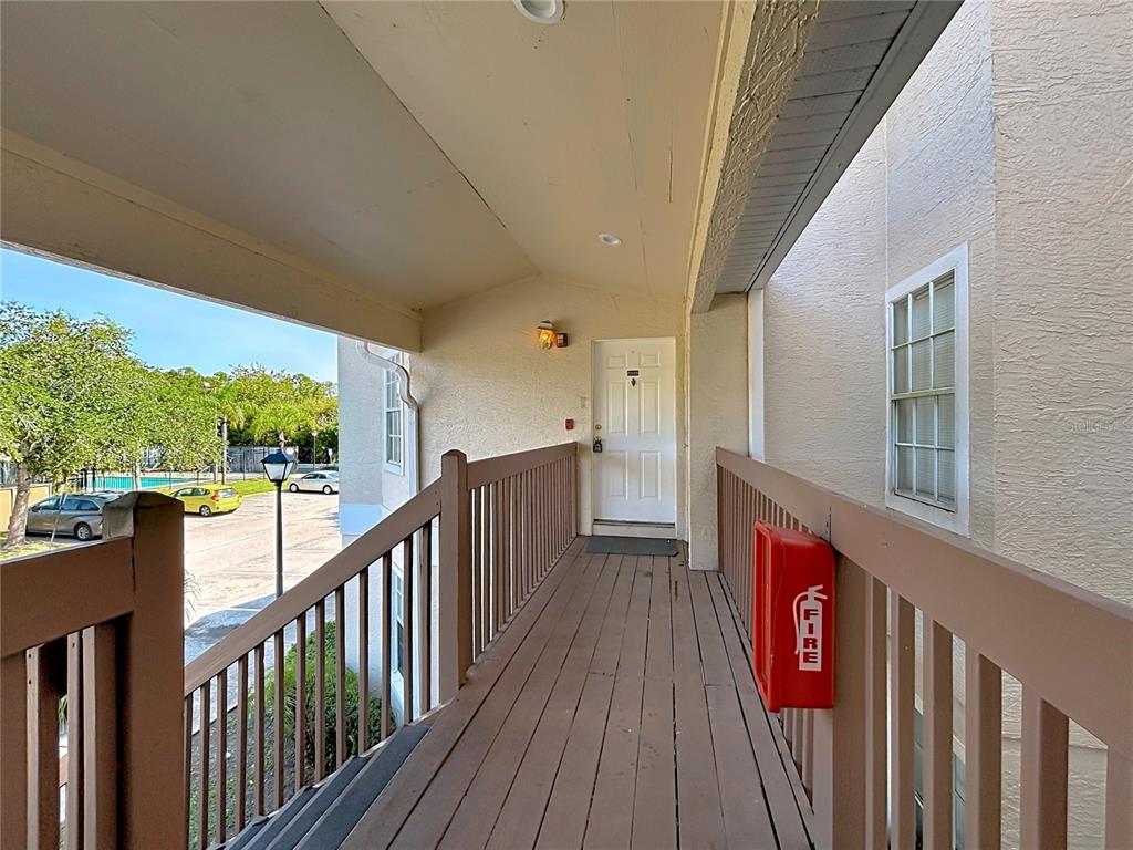An outdoor walkway leads to a white door with a red fire extinguisher box nearby — 2332 PRIME CIRCLE UNIT B, KISSIMMEE, FL