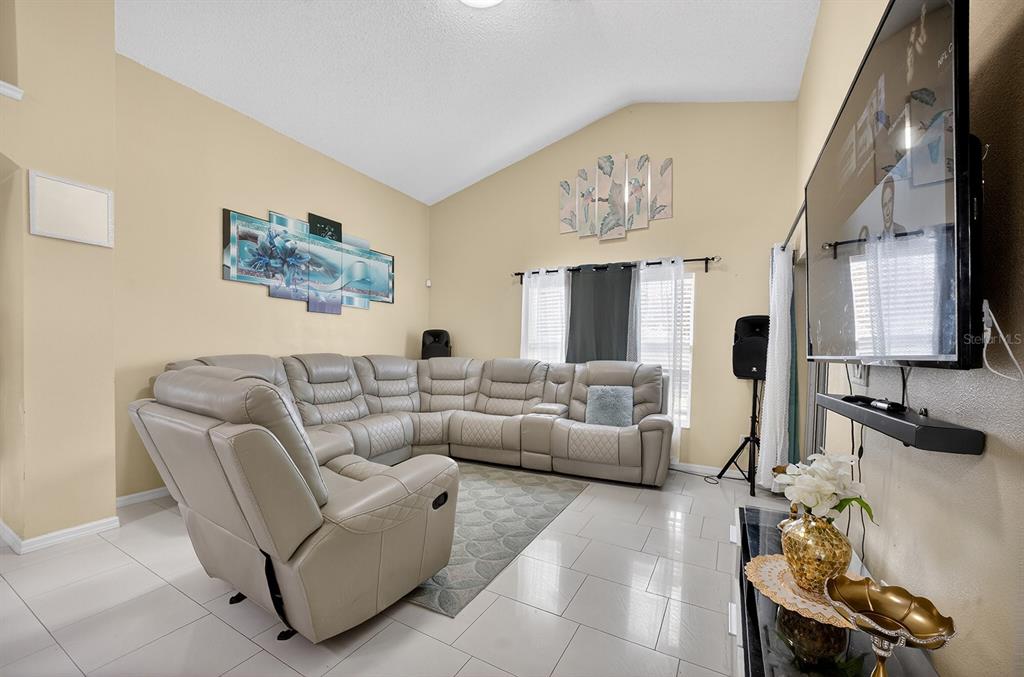 A living room features a large sectional sofa, tiled floors, and a wall-mounted television — 4524 SETTLEMENT CIRCLE, ORLANDO, FL