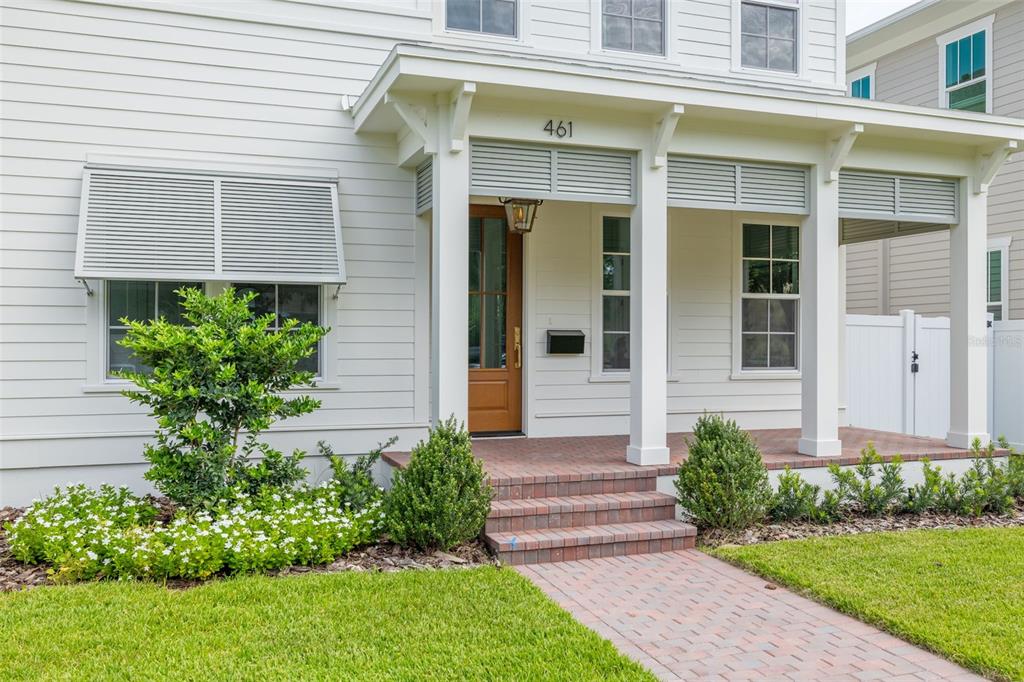 A white house exterior features a covered front porch with brick steps and landscaping — 461 47TH AVENUE N, ST PETERSBURG, FL