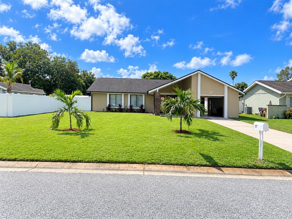 A single-story house with a white garage door, a concrete driveway, and a grassy lawn — 17 S FLAG DRIVE, KISSIMMEE, FL