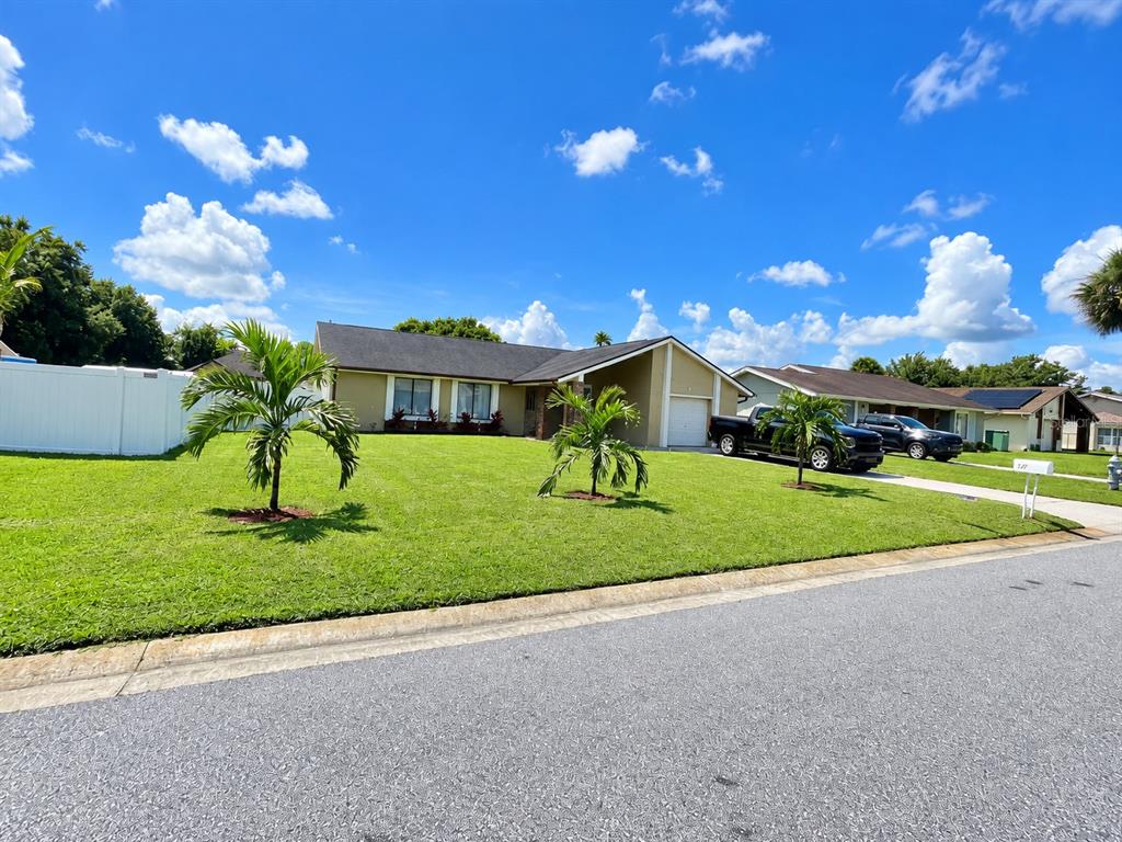 A backyard features a green lawn, a white vinyl fence, and an above-ground swimming pool — 17 S FLAG DRIVE, KISSIMMEE, FL