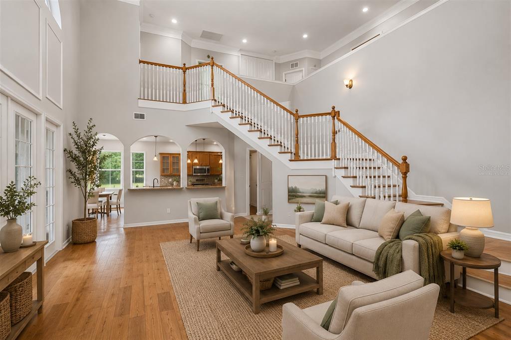 A living room with hardwood floors, a large staircase, and an open kitchen in back — 18326 SUCCESS ROAD, BROOKSVILLE, FL