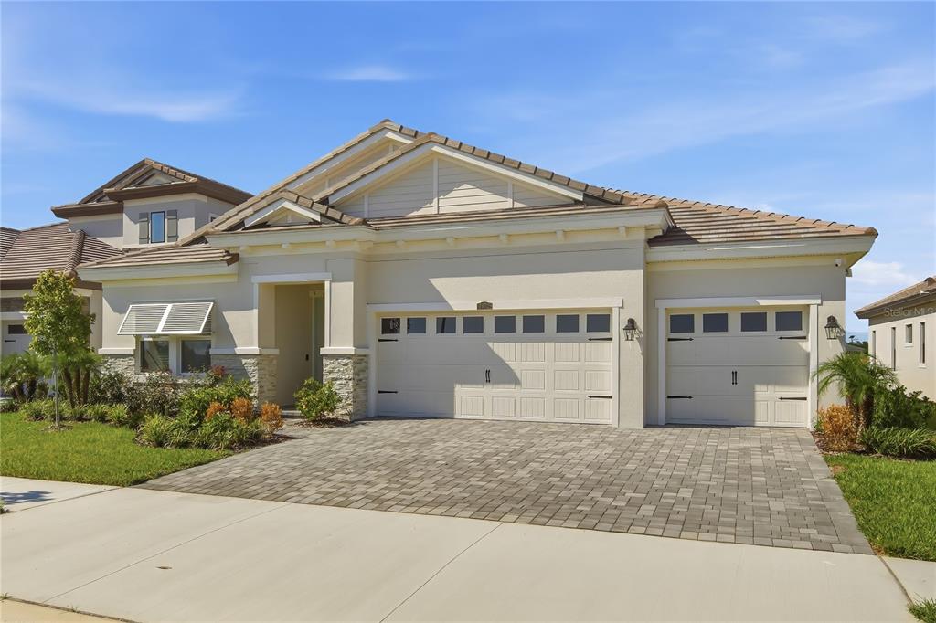 A single-story house with a beige stucco exterior, stone accents, and a three-car garage — 9632 SURREY ROSE DRIVE, SAN ANTONIO, FL