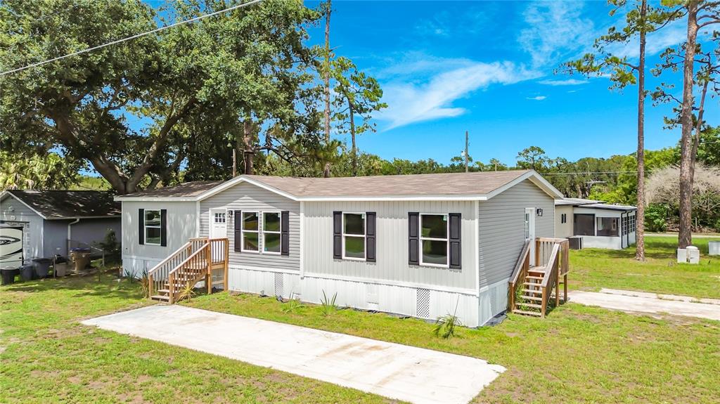 A light gray manufactured home with black shutters and two wooden entry staircases — 1657 FLOUNDER STREET, ST CLOUD, FL