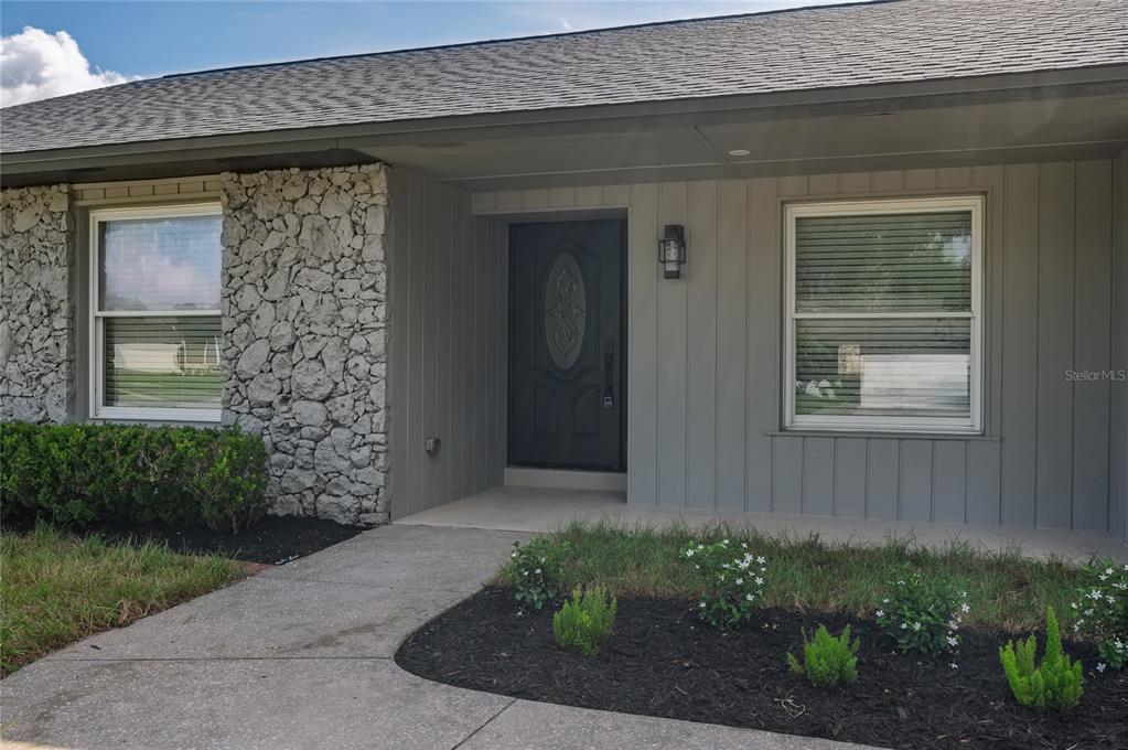 The exterior of a house features a stone facade, gray siding, and a front entrance — 5112 JEANNINE COURT, ORLANDO, FL