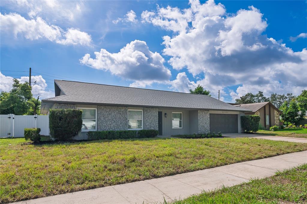 A single-story house with a gray stone facade, a two-car garage, and a lawn — 5112 JEANNINE COURT, ORLANDO, FL