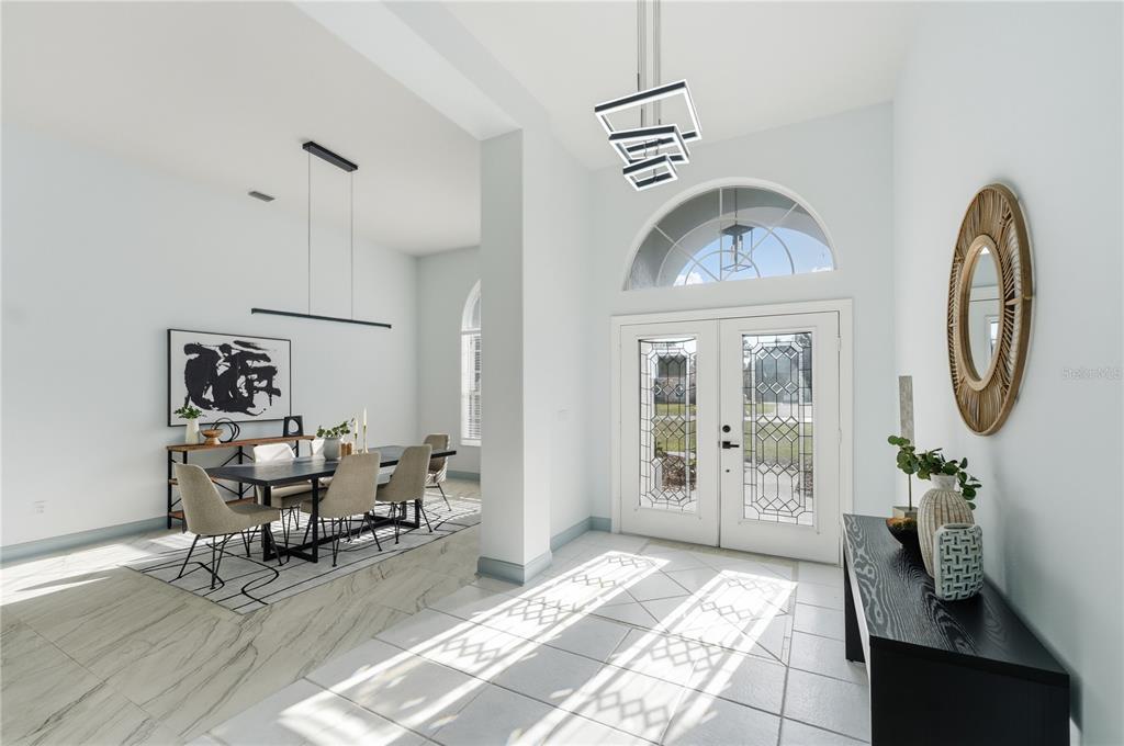 A bright entryway with tile floors leads to a dining area with a modern chandelier — 4873 NE 64 AVENUE, SILVER SPRINGS, FL