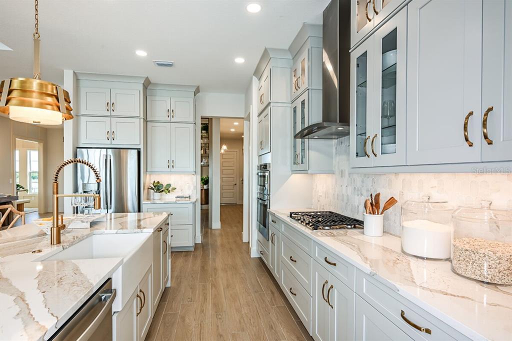 A modern kitchen features light gray cabinets, white marble countertops, and a farmhouse sink — 17524 MACARTHUR LOOP, VENICE, FL